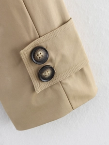 Close-up of khaki trench coat cuffs with tortoise shell buttons and stitching