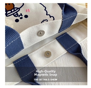 Detail shot of the magnetic snap closure on a white canvas tote with blue handles