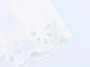 Detail der weißen hohlblumigen Stickerei und Wellenkanten an den Spitzenshorts