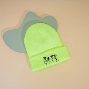 Gros plan du bonnet tricoté vert fluo avec broderie de quatre petits squelettes dansants
