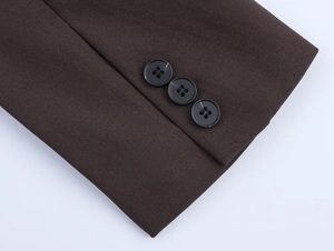 Close-up of brown blazer sleeve featuring three smooth black buttons and woven fabric texture