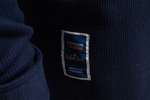 Close-up of fashion label on navy blue waffle knit jacket with textured fabric detail