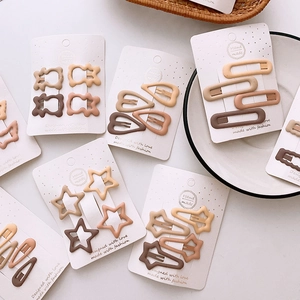 Detailed view of matte star and heart hair clips in earth tones on white display card