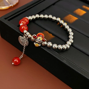 Macro shot of silver pearl bracelet with red agate beads and Fu character pendant