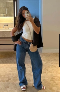 Mirror selfie showing blue wide-leg jeans with a white ribbed top and beige woven shoulder bag