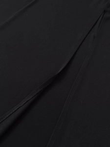 Detail of black crepe fabric showing high slit stitching and textile texture on dress