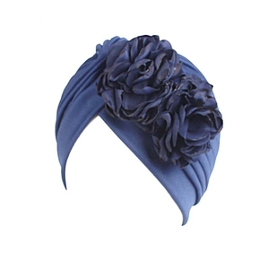 Detailed view of navy blue turban hat with dual layered floral ornaments on the side