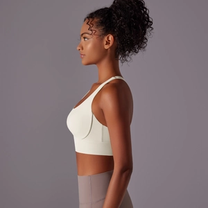 Dettaglio laterale del reggiseno sportivo beige incrociato e leggings yoga grigio scuro a vita alta
