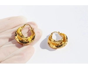 Detail shot of golden chunky hoop earrings with a handcrafted hammered metal texture