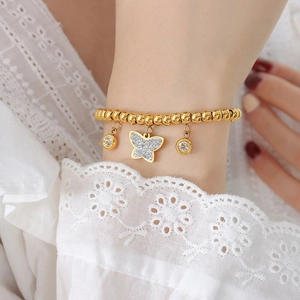 Golden butterfly and round crystal beaded titanium steel bracelet on a woman wrist
