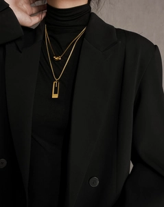 Close-up of double-layered gold titanium necklace with rectangular pendant on black clothing