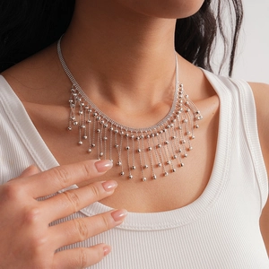 Detail of silver layered fringe necklace with metallic bead charms on an elegant model