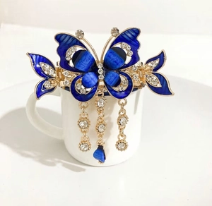 Detail of blue butterfly hair claw with gold metal frame, enamel wings and tassels