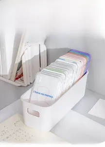 White plastic storage box with handles organizing multiple phone cases on a tidy desk