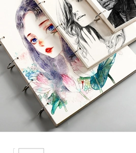 Close-up of linen cover sketchbooks with silver spiral binding and artistic illustrations