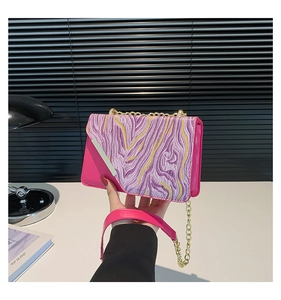 Pink shoulder bag detail showing marble pattern flap and golden metal chain strap accessory