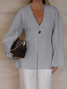 Detail of gray V-neck knit cardigan with a dark button and loose sleeves on model