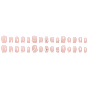 French tip press-on nails with nude pink base, white 3D flowers, and pearl accents