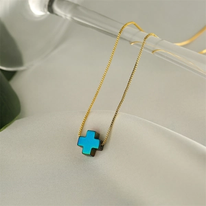 Detailed close-up of a golden box chain with a blue-green gradient cross pendant