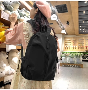 Rear view of a black lightweight casual backpack showing the zippers and side pockets