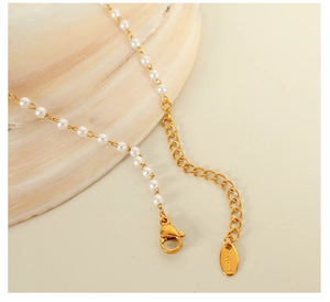 Dettaglio della collana di perle bianche con chiusura a moschettone dorata e catenina
