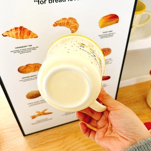 Close-up of cute ceramic mug base with Lovely pattern held by a hand in a cozy kitchen