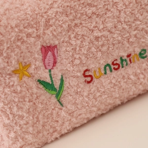 Detail of pink teddy fleece makeup bag featuring embroidered tulip and Sunshine text