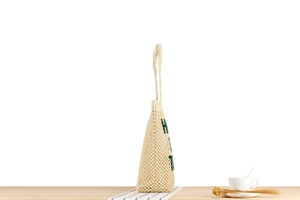 Détail d'un sac fourre-tout en maille tissée avec lettres vertes brodées et bretelles