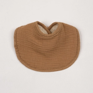 Close-up of caramel cotton muslin baby bib with absorbent layer and soft crinkle texture