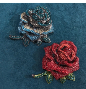 Close-up of rose brooches with blue and red rhinestones on a textured background