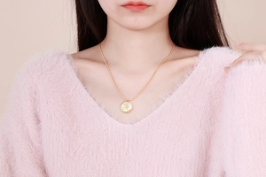 Close-up of golden Leo zodiac coin necklace with white shell inlay on a model