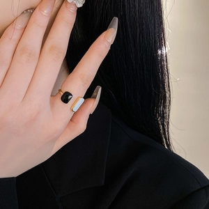 Close-up of geometric gold ring with black and white enamel detail on model finger
