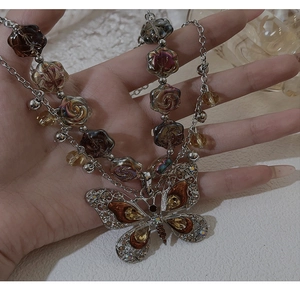 Macro shot of silver butterfly pendant with amber gemstones and iridescent floral beads