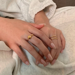 Detail of minimalist gold-plated double-layer and beaded open rings worn on hands