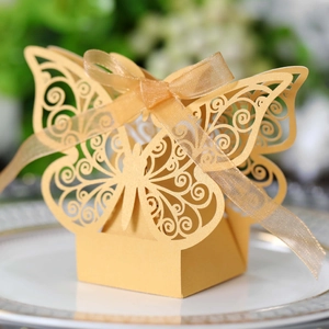 Macro view of golden butterfly laser-cut paper candy box with ribbon for wedding decor