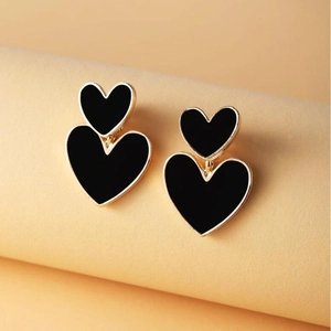 Close-up of double layered black heart dangle earrings with golden metal base