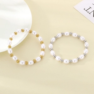 Dettaglio di bracciali con perle d'acqua dolce e sfere in oro e argento su superficie