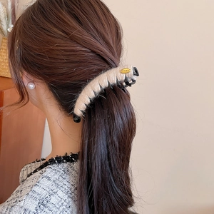 Gros plan d'une pince à cheveux en peluche beige sur un mannequin pour chignon élégant