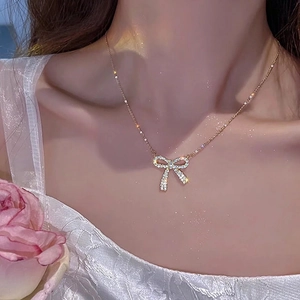 Elegant bow pendant necklace with sparkling cubic zirconia worn on a neck with a rose