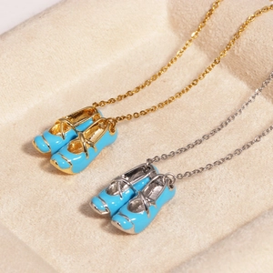 Close-up of gold and silver ballet slipper necklaces with blue enamel pendants
