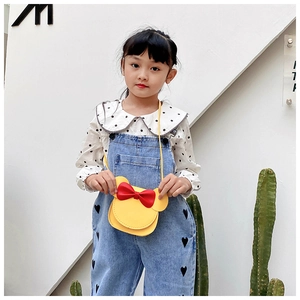 Close-up of yellow children's bow crossbody bag on model with polka dot shirt