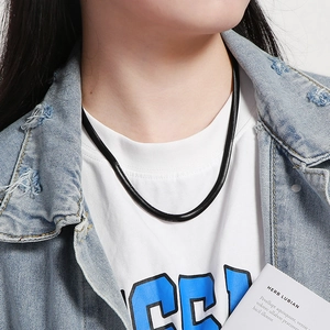 Close-up of black snake bone chain necklace on male model wearing a white tee and denim