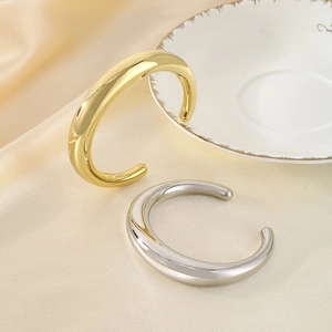Vue détaillée des bracelets en forme de C or et argent sur un tissu en soie champagne