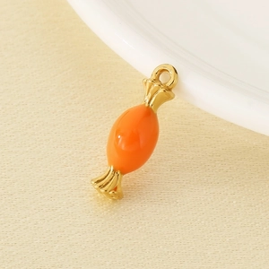 Macro detail of orange enamel candy pendant with gold trim for DIY jewelry making