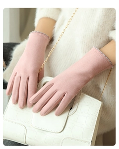 Close-up of pink faux suede gloves with patterned cuffs held with a white handbag