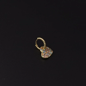 Detail of gold huggie hoop earring with bead texture and a colorful pavé heart pendant