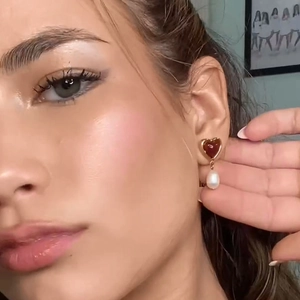 18k gold plated heart earrings with red inlay and drop pearl on a female model