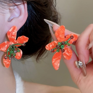 Detail of orange floral stud earrings with marbled petals and green beaded centers
