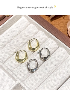 Detail view of gold and silver U-shaped polished earrings in a premium jewelry box