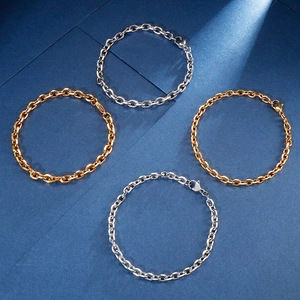 Flat lay of polished gold and silver stainless steel O-link chains on dark blue background